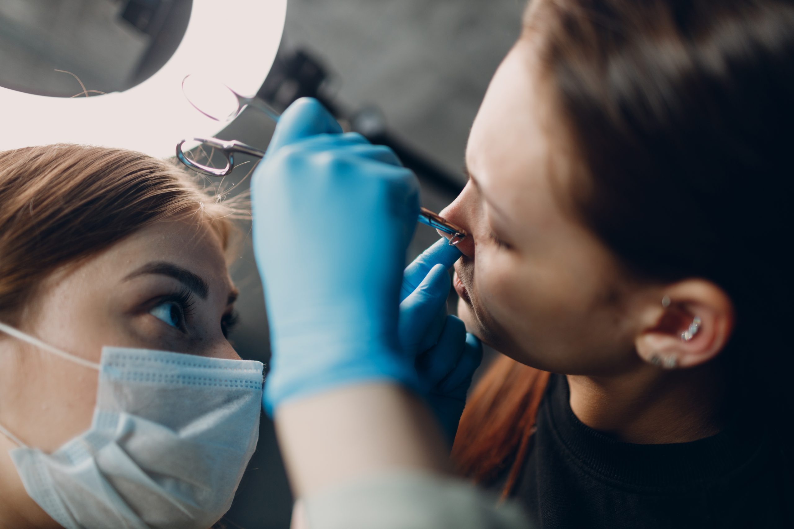 Young woman doing piercing at beauty studio salon.